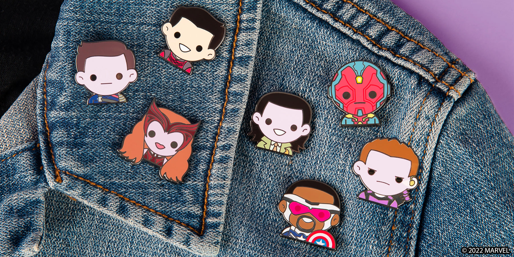 enamel pin collection featuring emojis from Hawkeye, WandaVision, Loki, and more pictured on a jean jacket