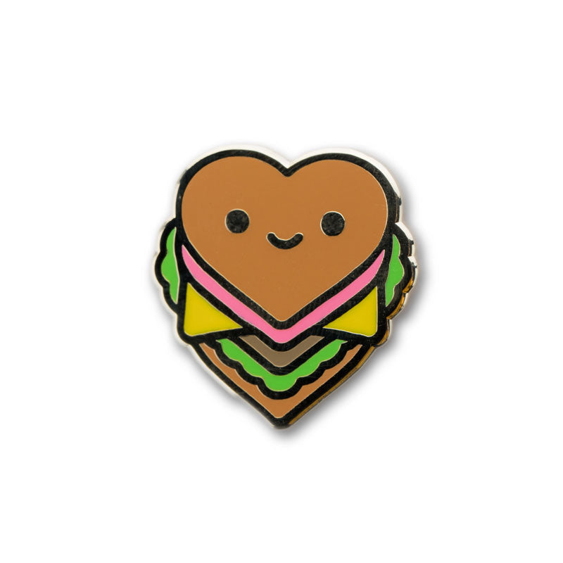 A pin of a burger in the shape of a heart pictures on a white background. 