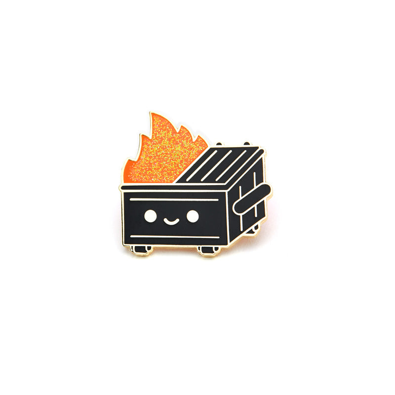 A pin of a black smiling dumpster fire with orange glitter flames. 